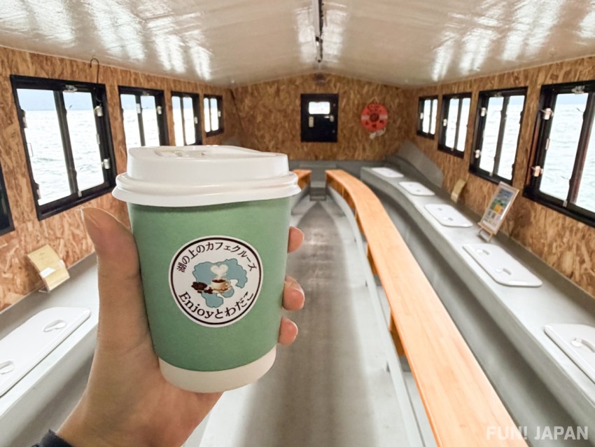 Enjoying coffee on a boat during the Lake Towada morning cruise